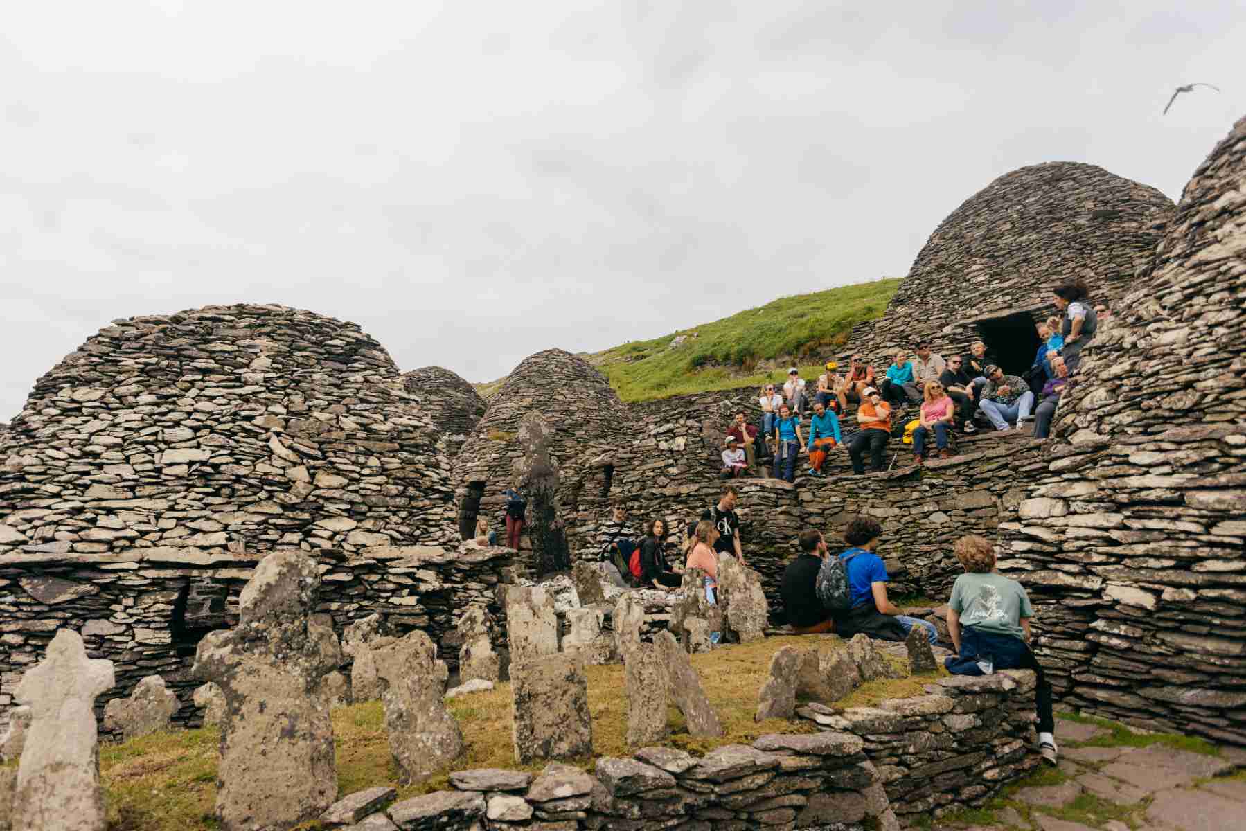Visitors sit and listen to a guided talk among the ancient dry-stone beehive huts at the Skellig Michael monastery