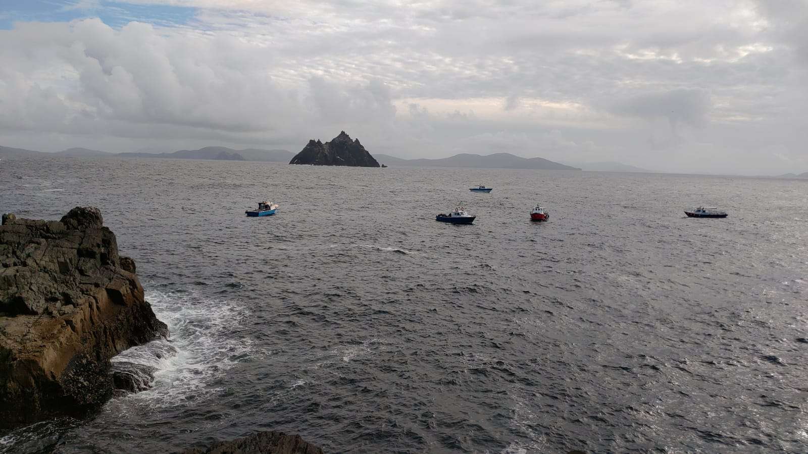 Small boats on the sea, with Skellig Michael in the distance