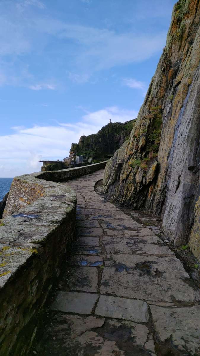 Stone landing path on Skellig Michael with rusted chain handrails leading up from the boat landing area