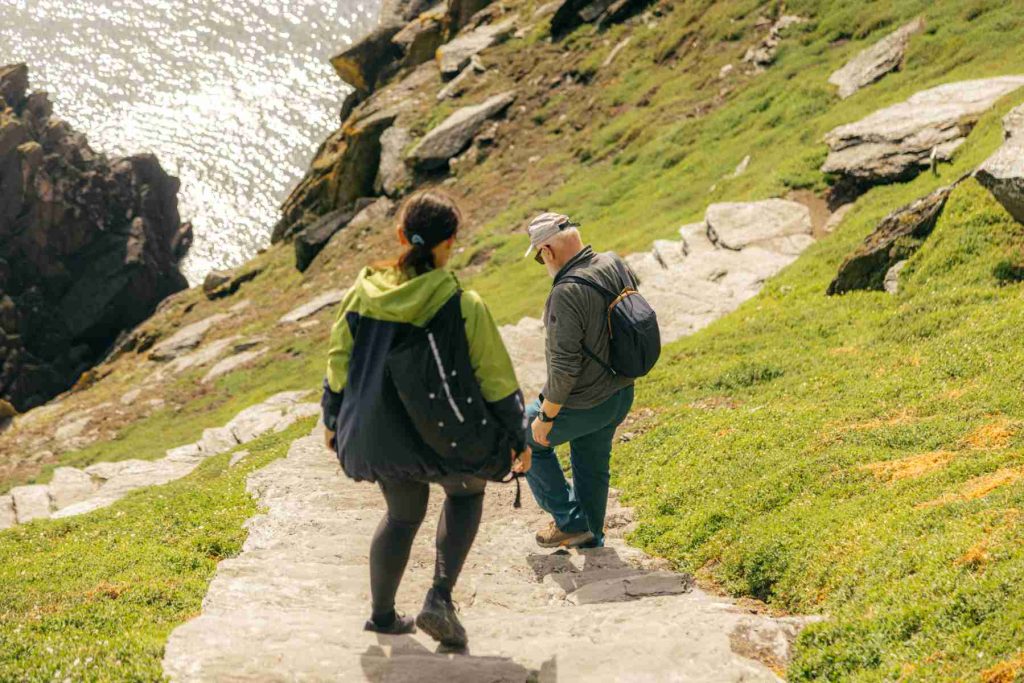 Two visitors walking down the stone path on Skellig Michael