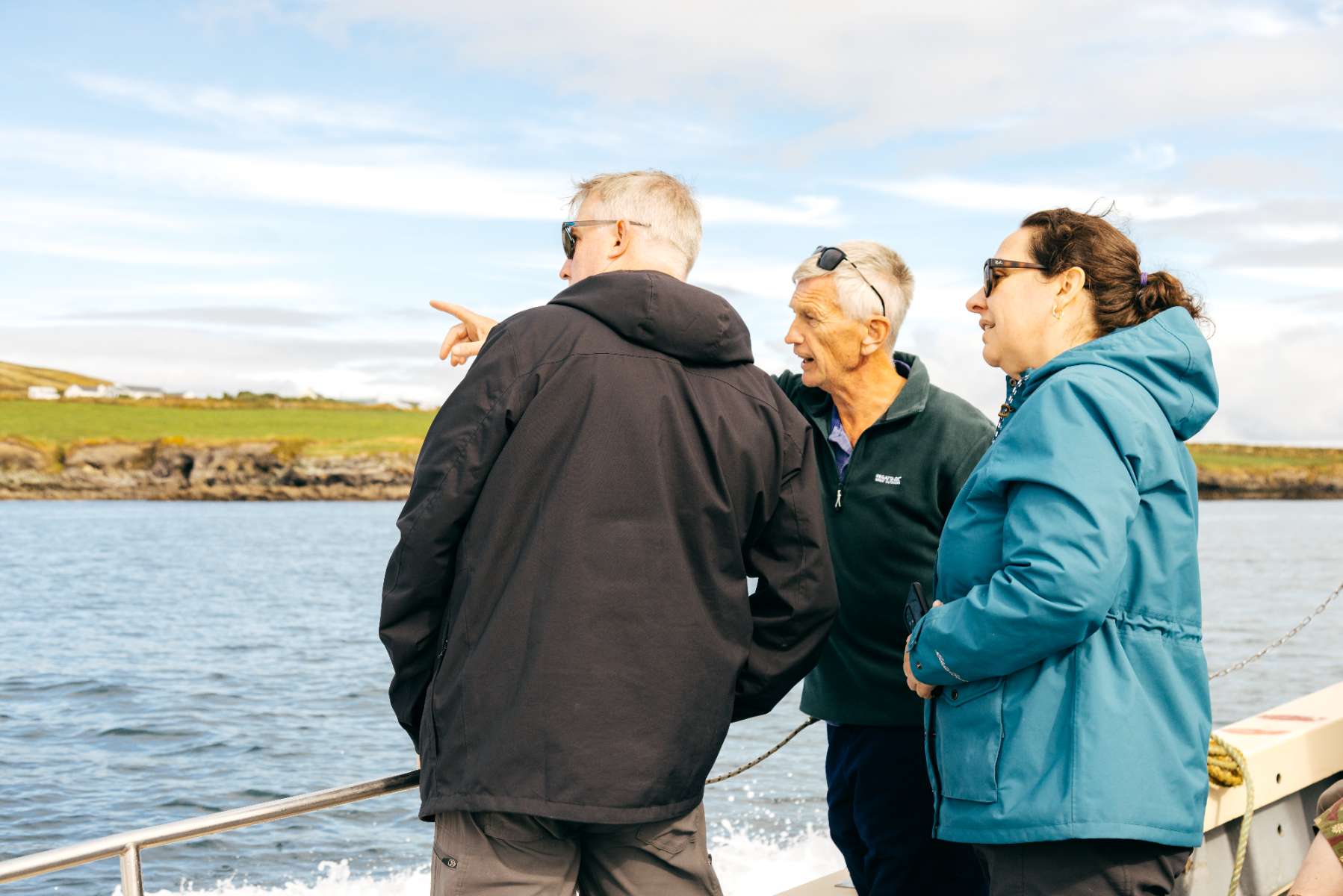 Three passengers on the boat, one pointing at the coast